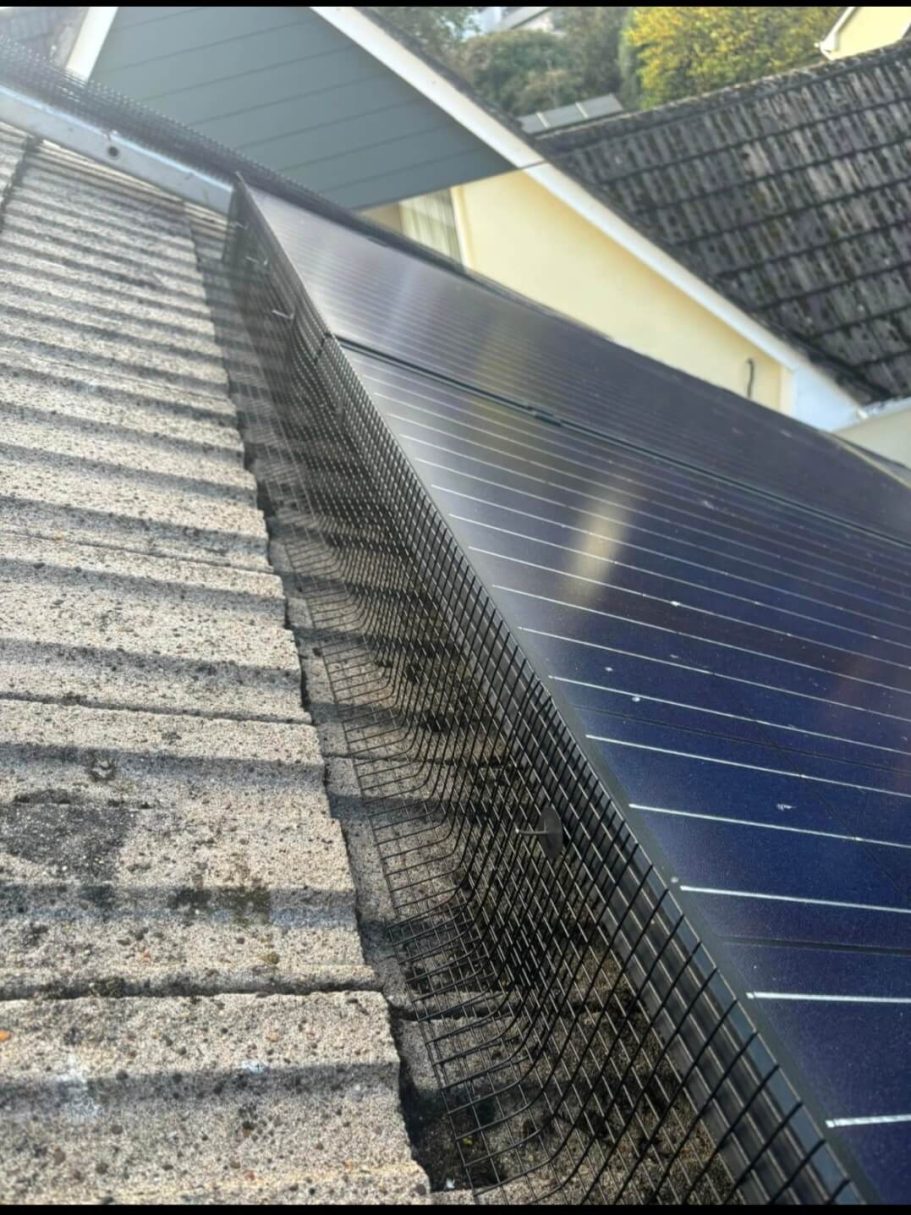Solar mesh installation Solar panels mounted on a sloped roof, next to tiled roofing.