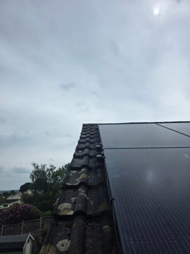 Solar panel Protection In Devon Solar panels installed on a sloped roof, with a cloudy sky in the background.
