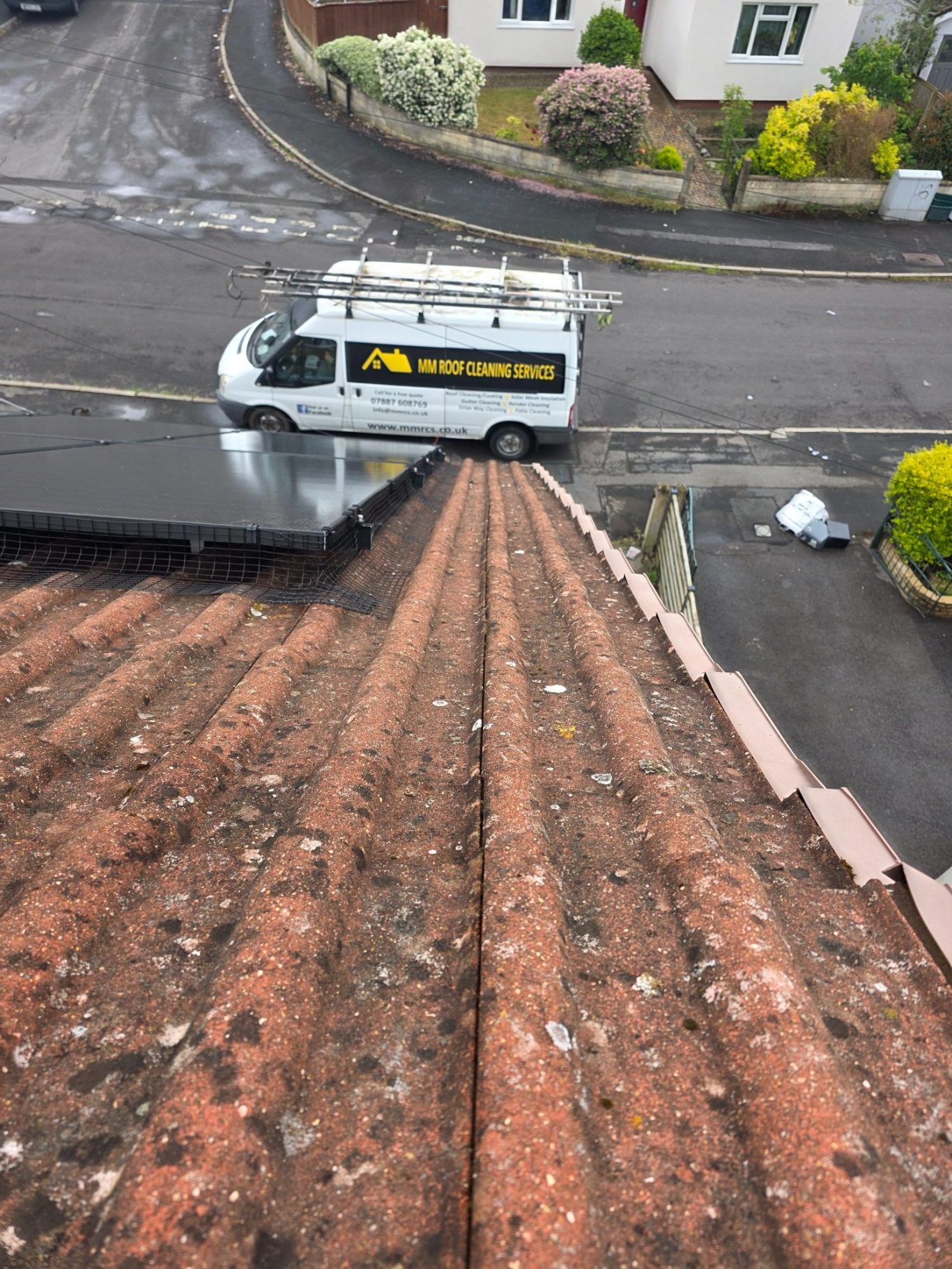 Solar panel mesh installation Bristol Solar panels on a roof with a box and debris near the edge of the gutter.