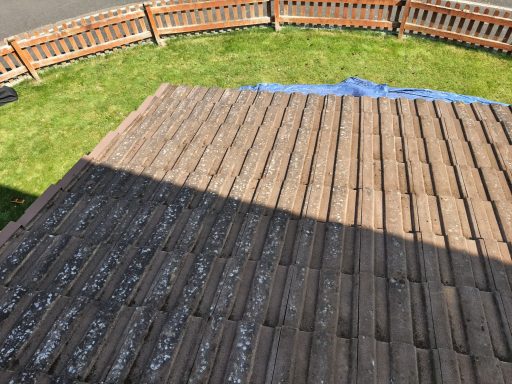 View of a sloped roof with alternating shaded and sunlit areas, surrounded by grass.