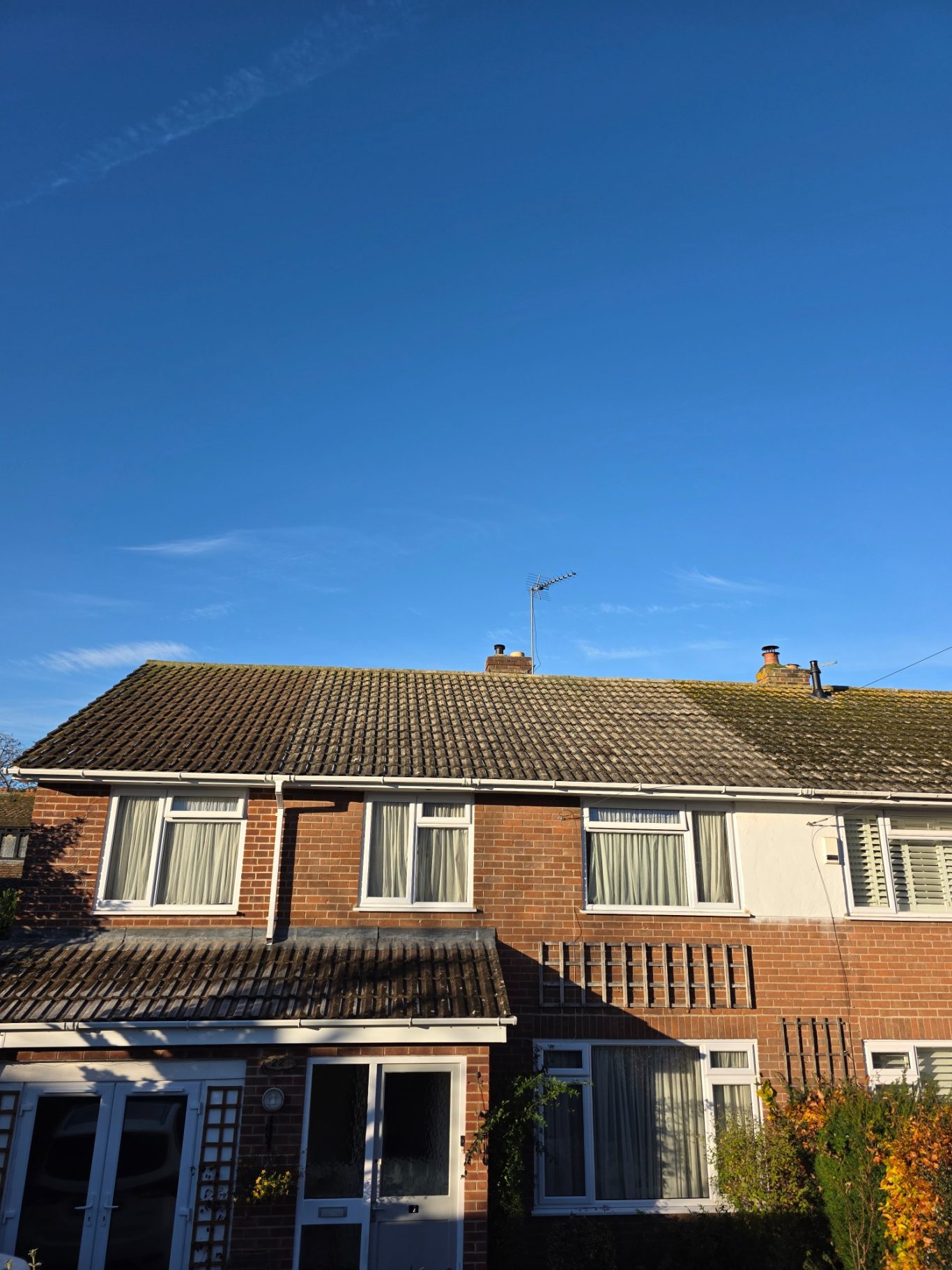 After the moss removal in Taunton A semi-detached house under a clear blue sky.