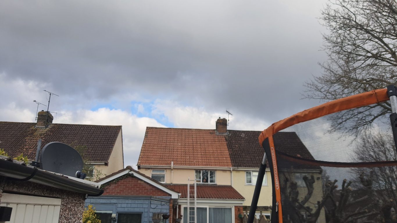 Roof cleaning Houses with cloudy sky, a trampoline in the foreground.