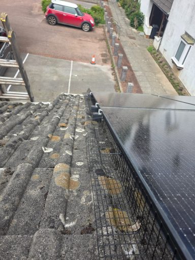 Solar panel Protection In Devon Solar panels on a sloped roof with a car parked nearby.