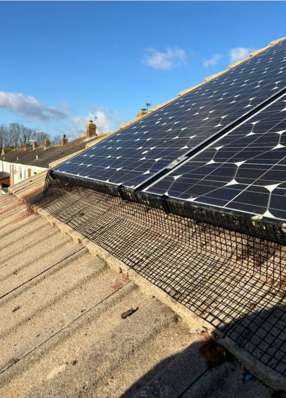 Solar mesh installation Solar panels installed on a tiled roof under a clear blue sky.