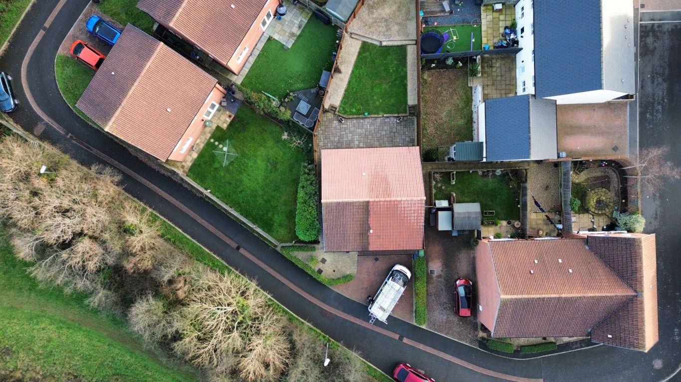 Low pressure wash and biocide treatment in Wellington Aerial view of suburban houses with driveways and gardens, alongside a winding road.