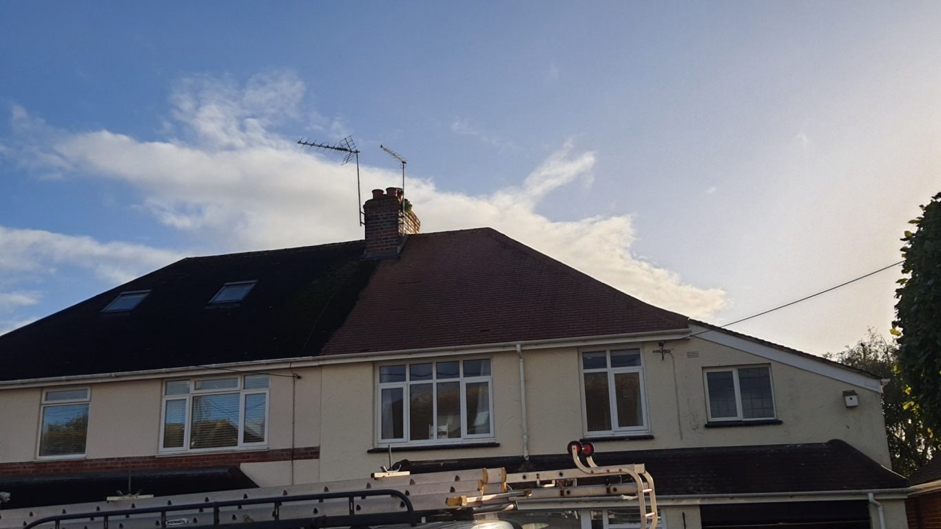 Moss Removal A two-storey house with a sloped roof and clear blue sky above.