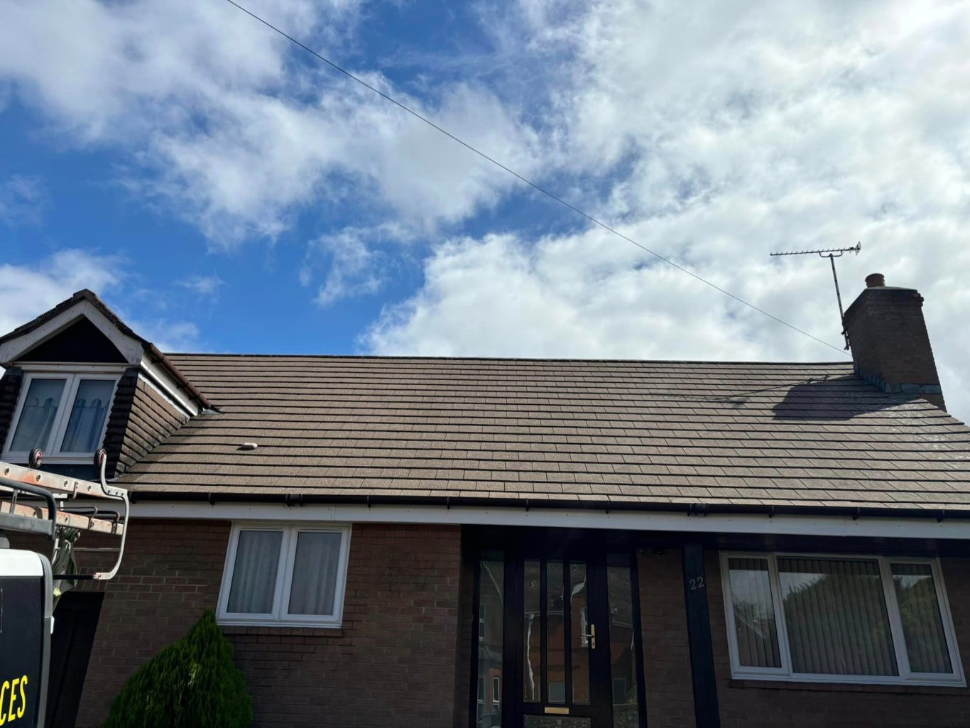 Roof Cleaning View of a house with a sloped roof under a partly cloudy sky.