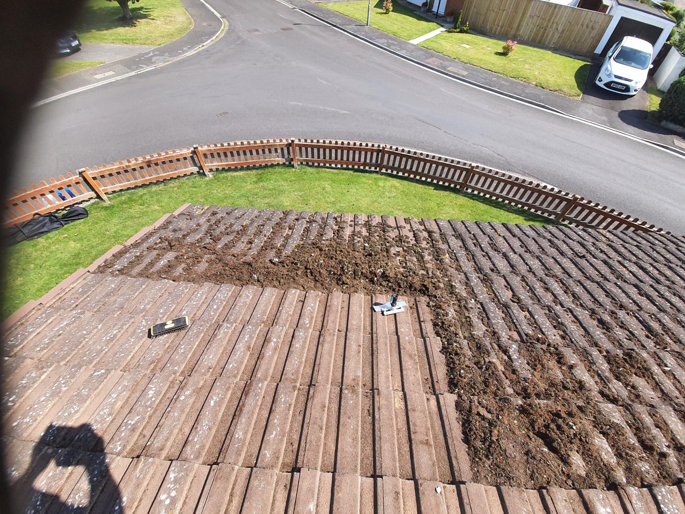 Moss Removal A partially cleared wooden deck, with dirt and tools visible, near a circular driveway.